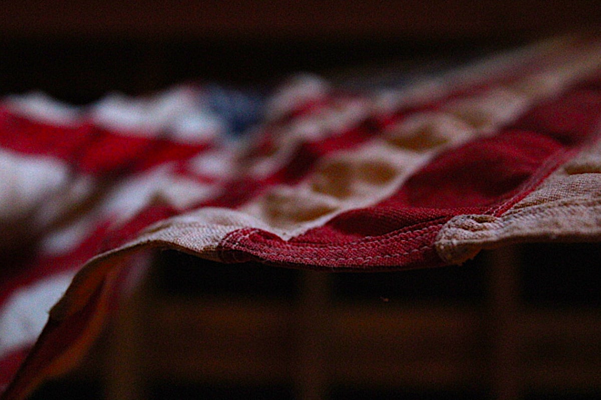 A worn, faded American flag lying in shadow