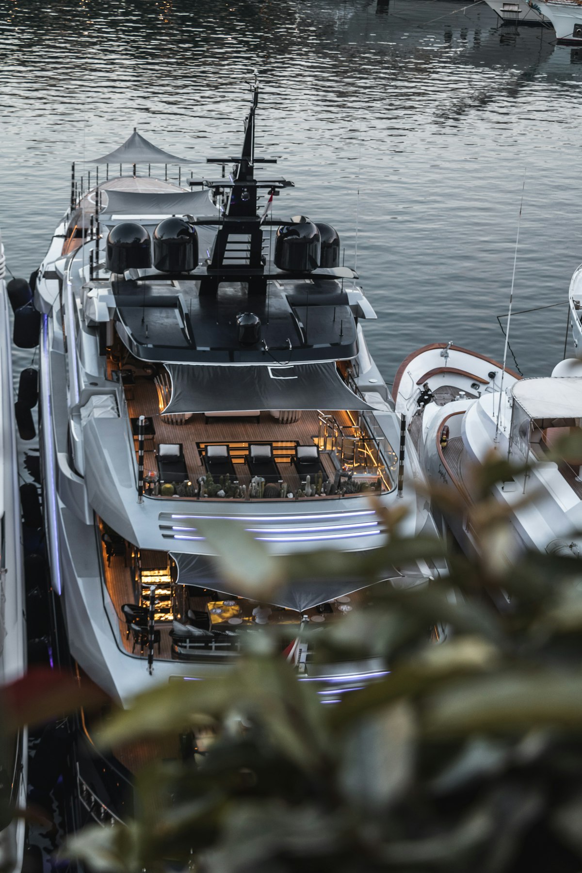 A gleaming superyacht moored and lit up at dusk